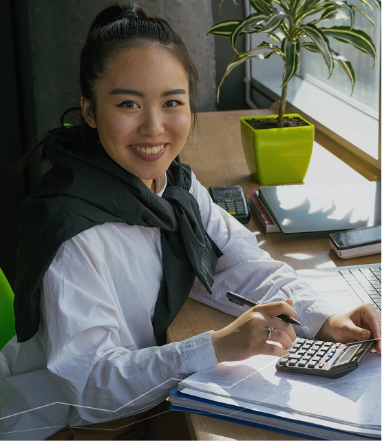 Person studying with calculator, notebook, and laptop at desk