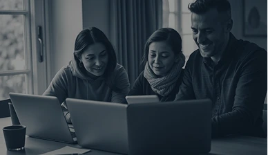 Three people collaborating with laptops at table